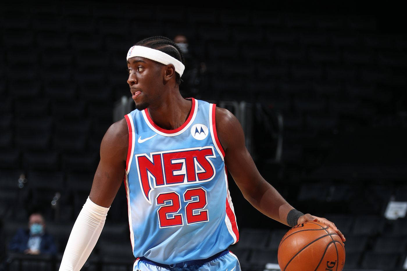 caris levert 桌布 壁紙 — 一名身穿淺藍色籃網隊球衣、號碼22的籃球運動員在明亮的場館燈光下於比賽中運球。
