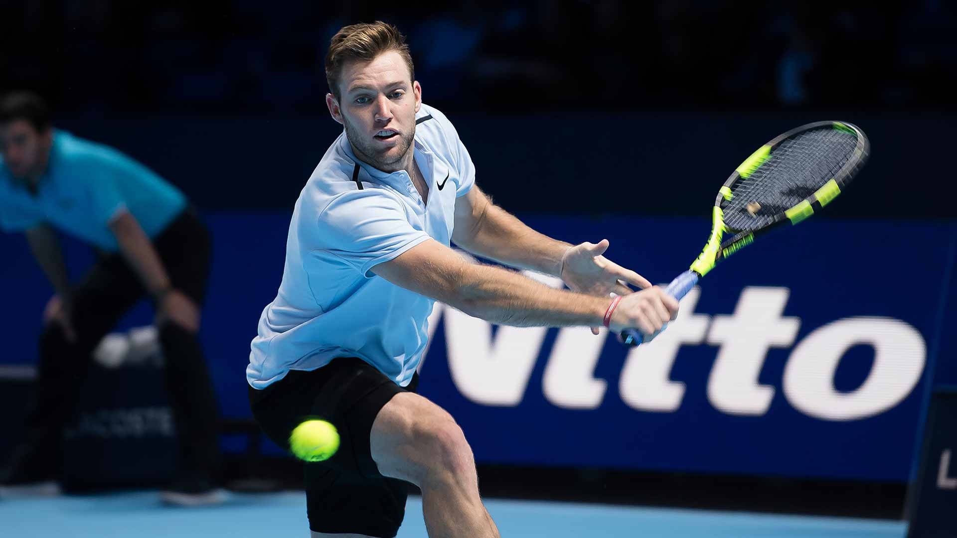 Tennis 桌布 壁紙 — 一名身穿淺藍色襯衫和黑色短褲的男性網球運動員，在藍色球場上揮動螢光綠色球拍擊打黃色網球。