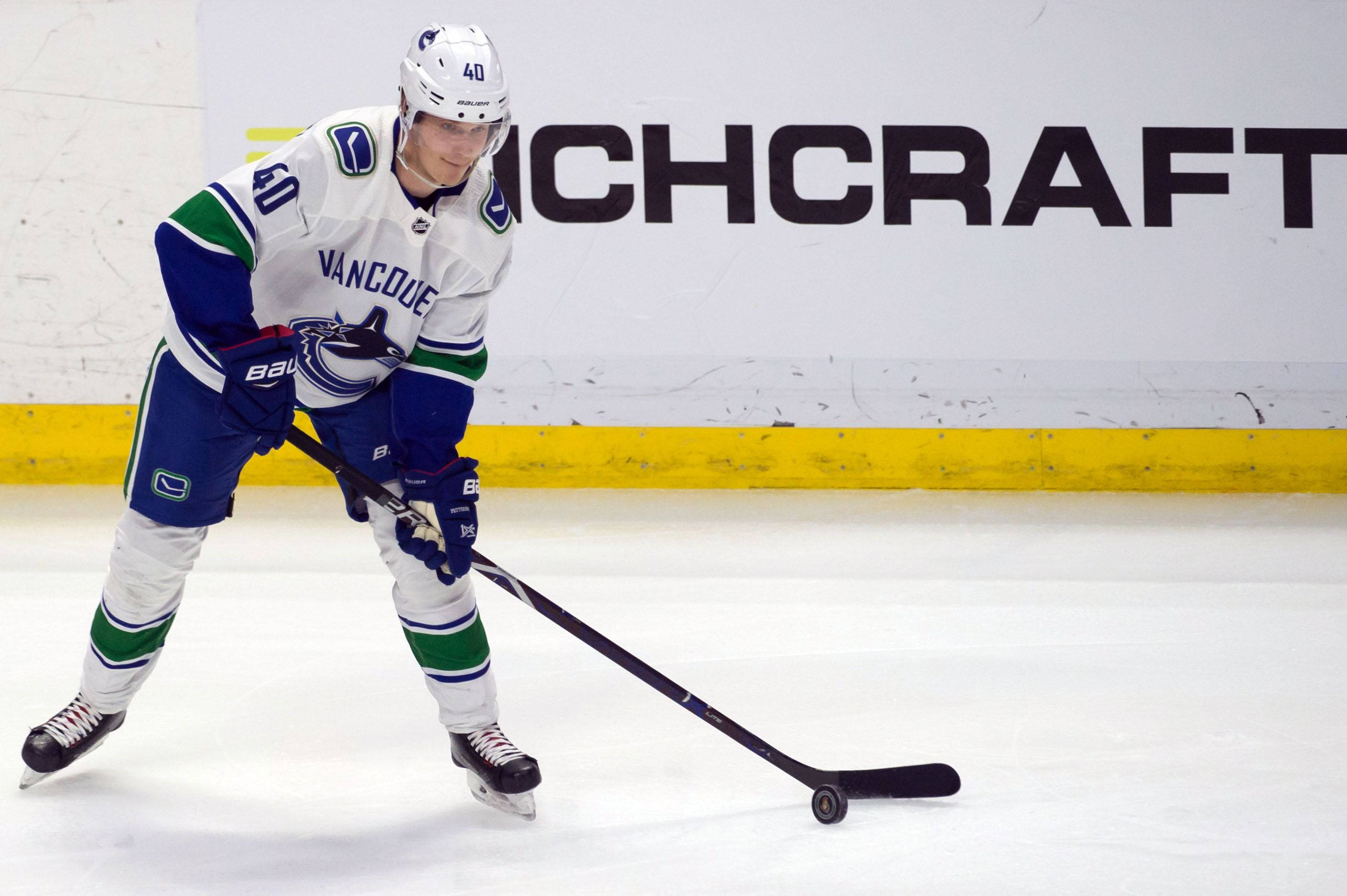 hockey 桌布 壁紙 — 一名身穿溫哥華加人隊（Vancouver Canucks）球衣的冰上曲棍球運動員，手持球桿在冰場上向前滑行。