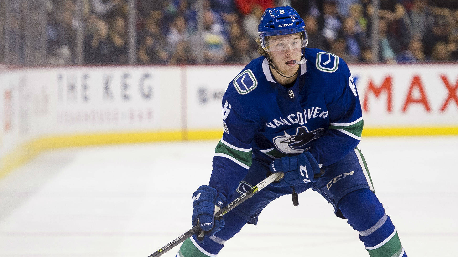 運動 桌布 壁紙 — 一名身穿溫哥華加人隊（Vancouver Canucks）藍色球衣的冰球運動員，在冰上專注而激烈地滑行。