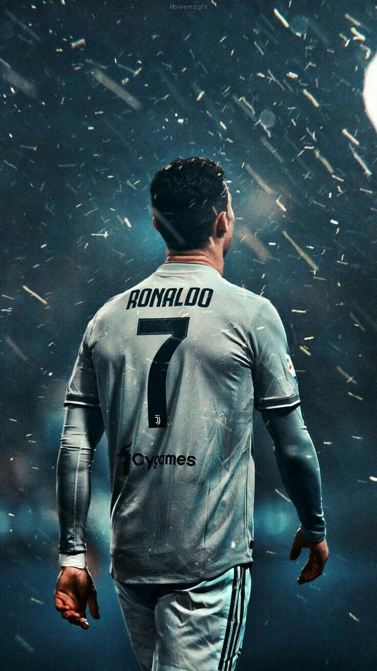 Ronaldo 桌布 壁紙 — 一名身穿灰色7號球衣的足球員背向觀眾站立，金色粒子在戲劇性的球場聚光燈下灑落。