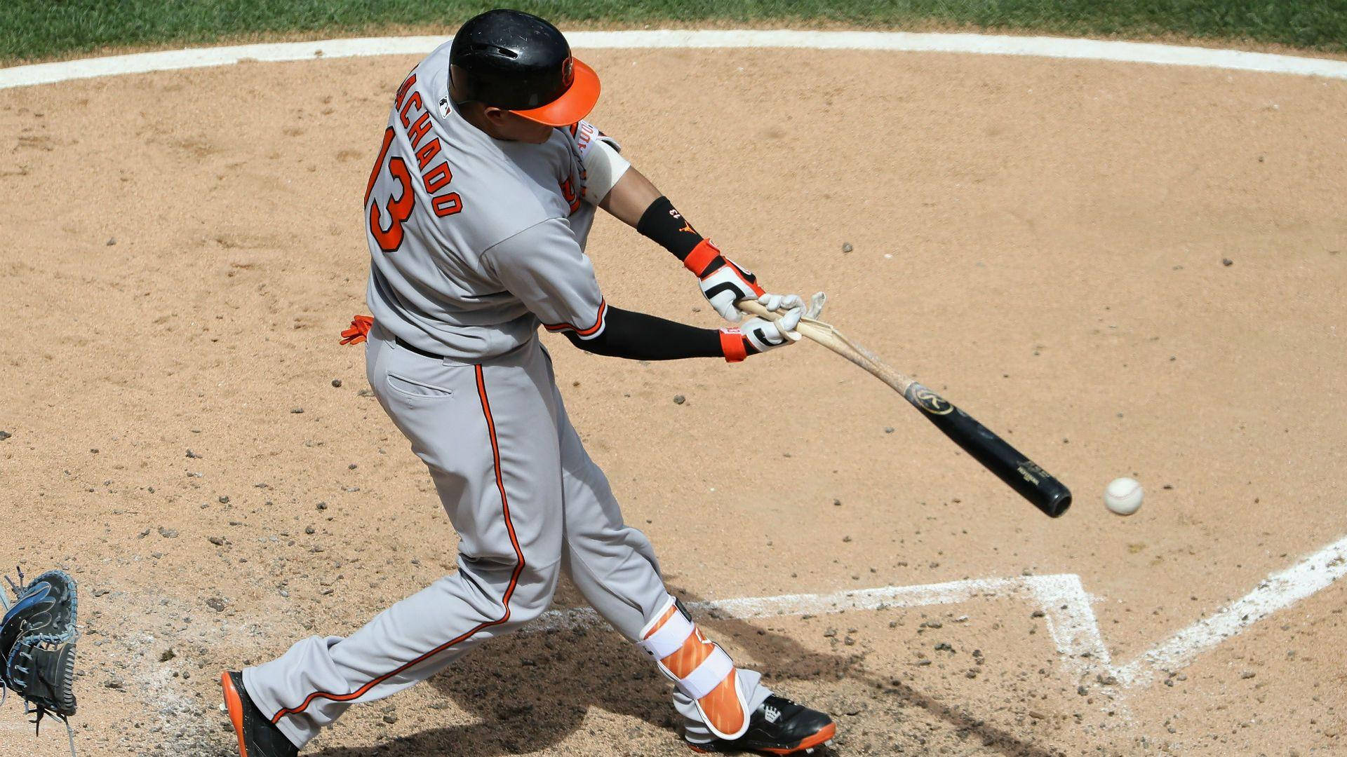 Machado 桌布 壁紙 — 一名身穿灰色和橙色球衣的棒球選手在陽光照耀的泥地球場上揮棒擊球。