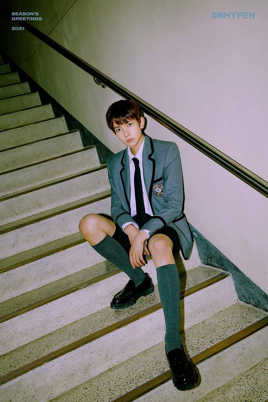 Kpop Aesthetic 桌布 壁紙 — 一名身穿灰色校服的年輕男子坐在混凝土樓梯上，樓梯帶有金屬扶手，處於柔和室內燈光下。