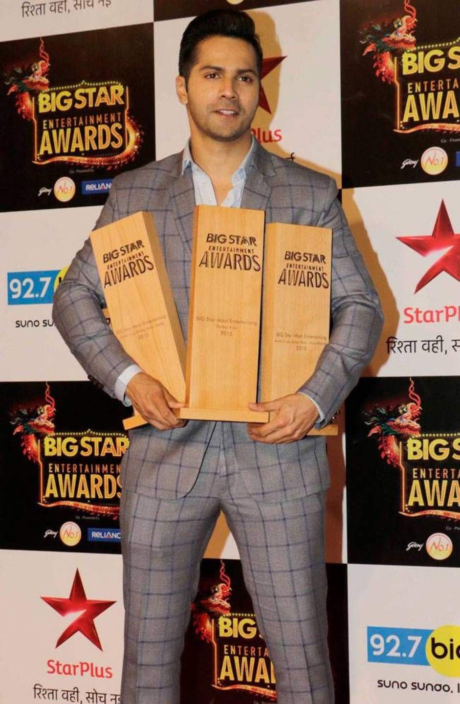 Varun 桌布 壁紙 — 一名身穿灰色格紋西裝的男子在Big Star Entertainment Awards記者會上手持三個木製獎盃。