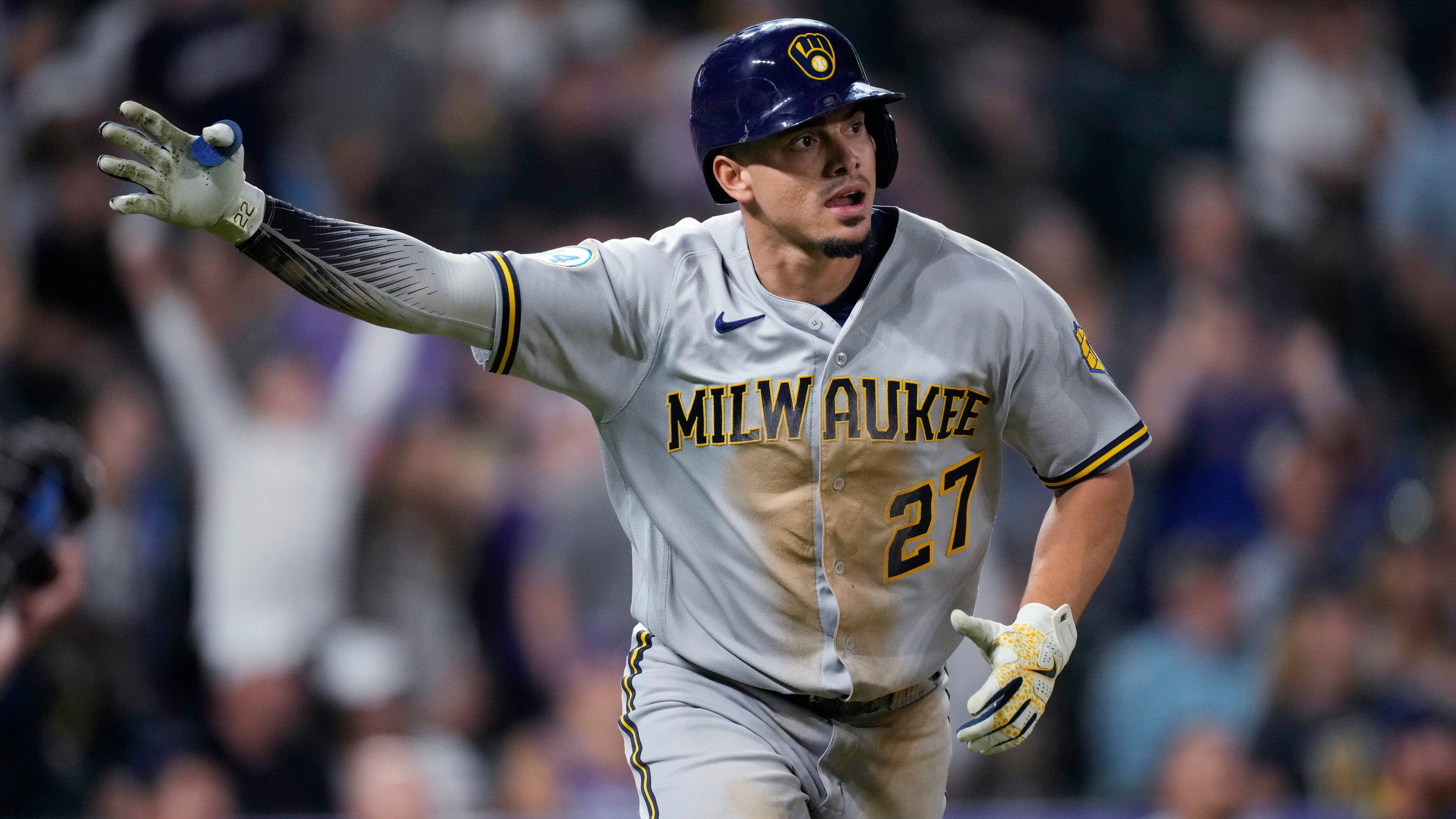 Brewers 桌布 壁紙 — 一名身穿灰色球衣、背號27的密爾瓦基釀酒人棒球選手，在夜間比賽中衝過球場，球場燈光照亮他堅定的表情。