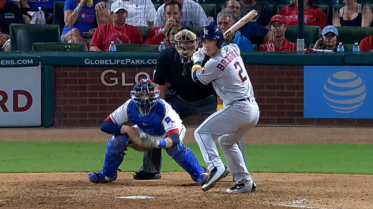 Bregman 桌布 壁紙 — 一名身穿灰色球衣的棒球打者揮棒擊球，而一名身穿藍色裝備的捕手在球場燈光下蹲在本壘板後方。
