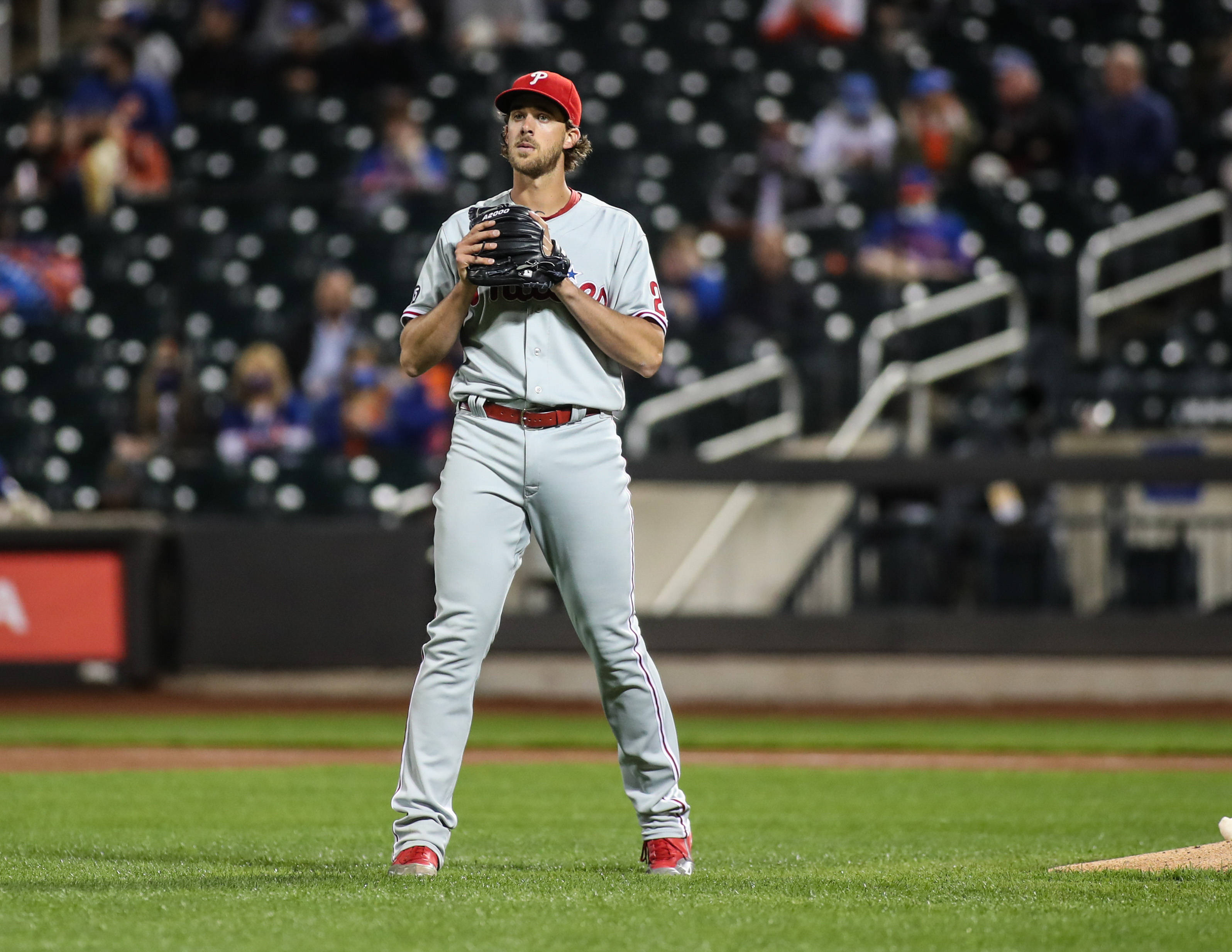 Phillies 桌布 壁紙 — 一名身穿灰色球衣的棒球投手在球場燈光下，於綠色場地上擺好姿勢，背景有模糊的觀眾。