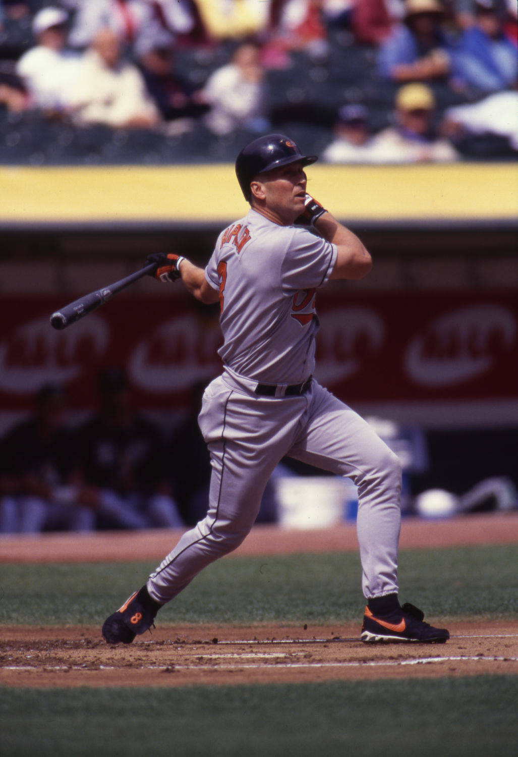 cal ripken jr 桌布 壁紙 — 一名身穿灰色球衣的棒球選手在陽光普照的球場上揮棒，背景有觀眾。