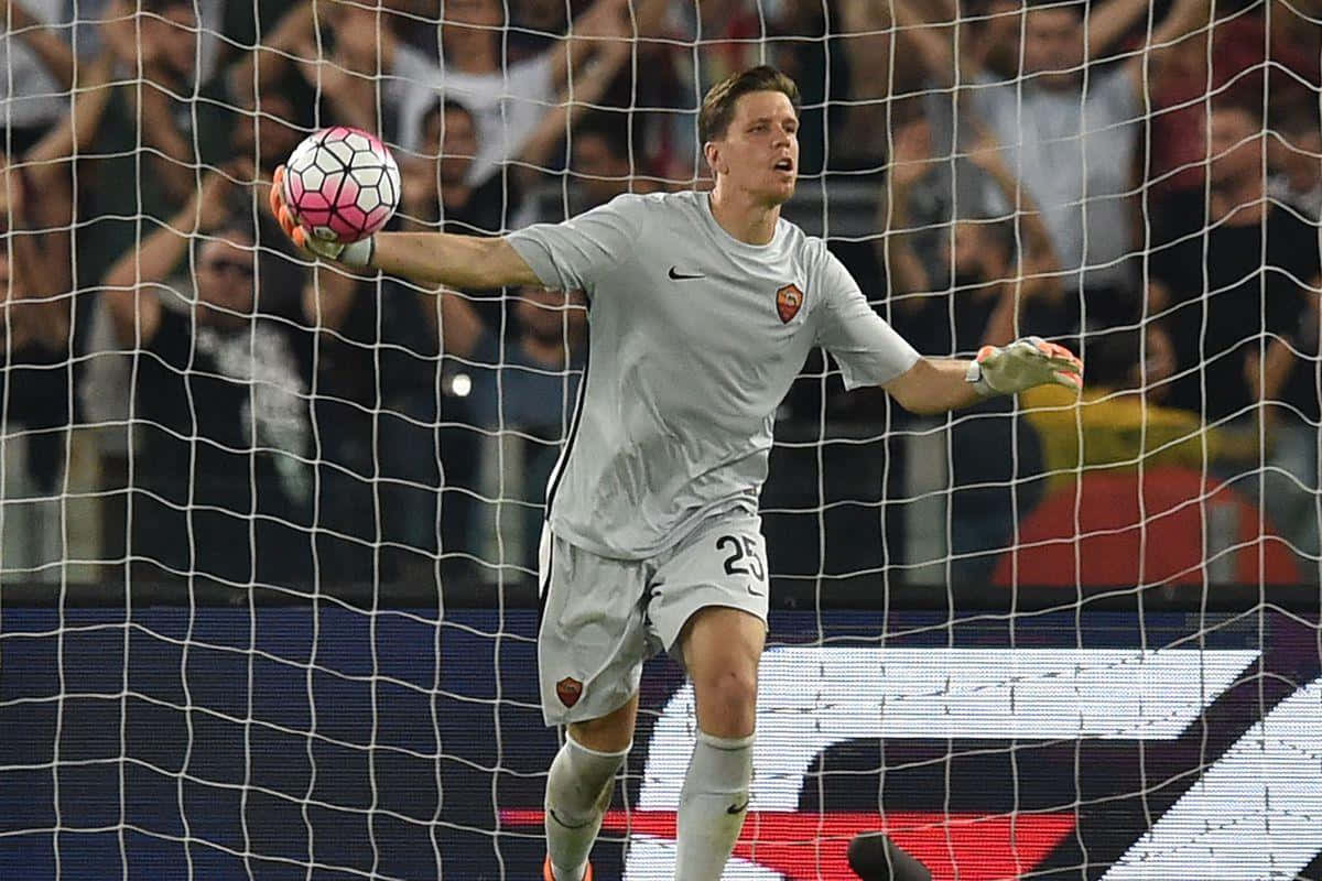 Wojciech Szczesny 桌布 壁紙 — 一名身穿灰色球衣的足球守門員在比賽中專注地在球網前接住一個粉紅和白色的球。