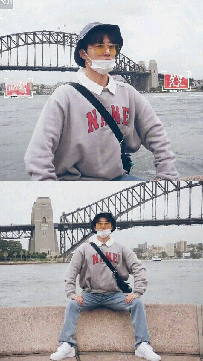 kim hanbin 桌布 壁紙 — 一名身穿灰色運動衫和漁夫帽的人坐在石台上，背景是雪梨港灣大橋。