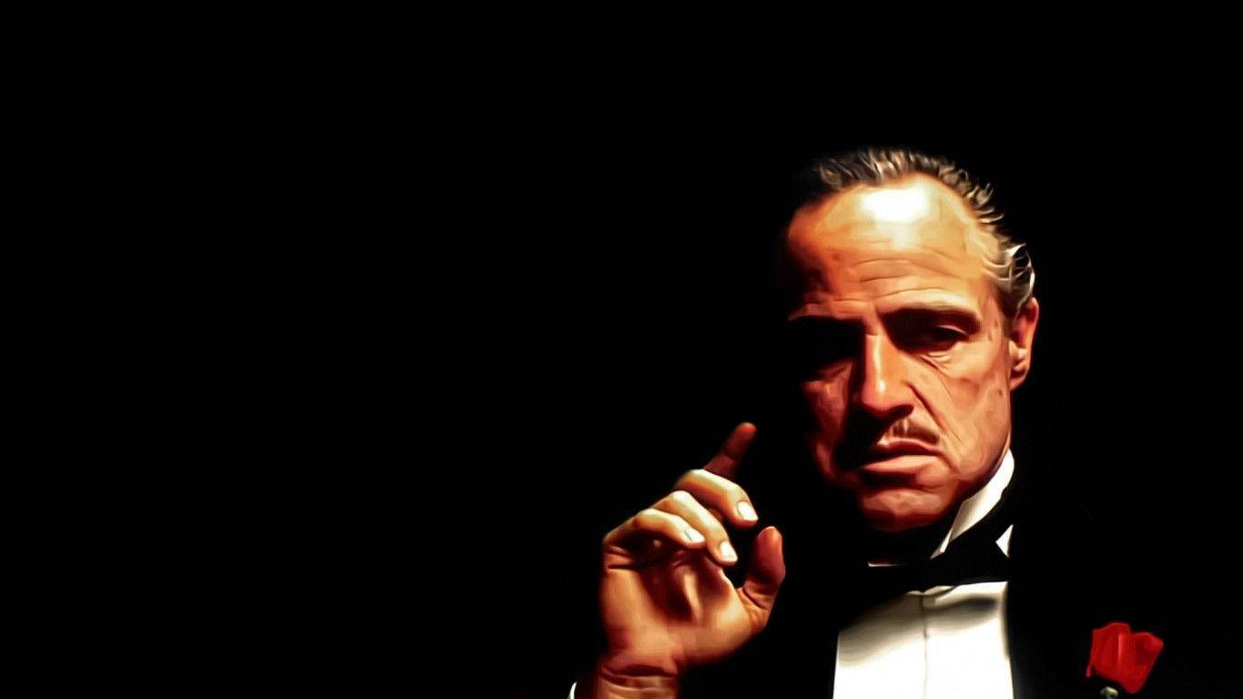 Godfather 桌布 壁紙 — 一名身穿燕尾服、佩戴紅玫瑰胸針的男子在戲劇性燈光下，於黑色背景前舉起手指。