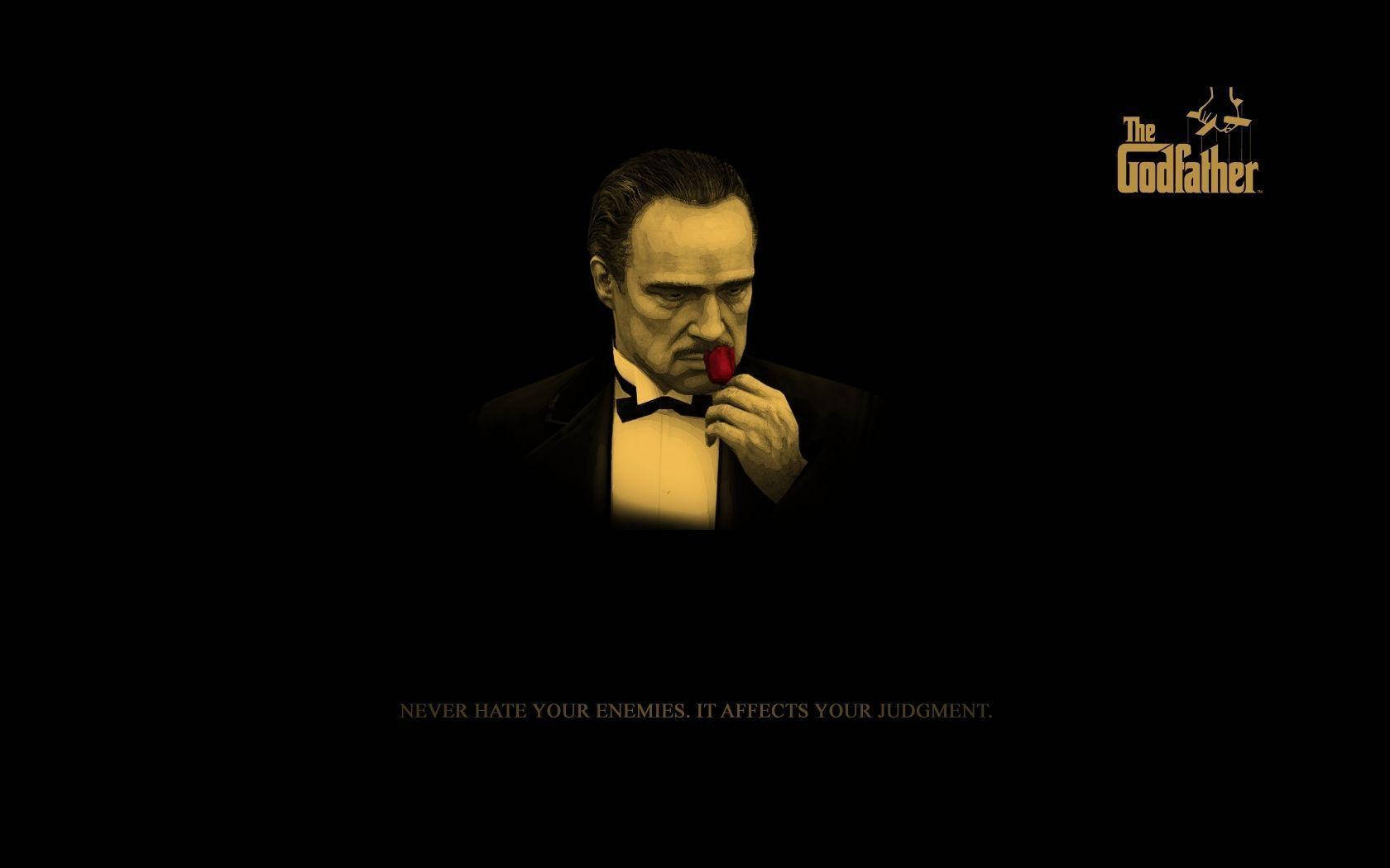 Godfather 桌布 壁紙 — 一名身穿燕尾服的男人在黑色背景前將紅玫瑰貼在唇邊，並有《教父》標誌和引文。