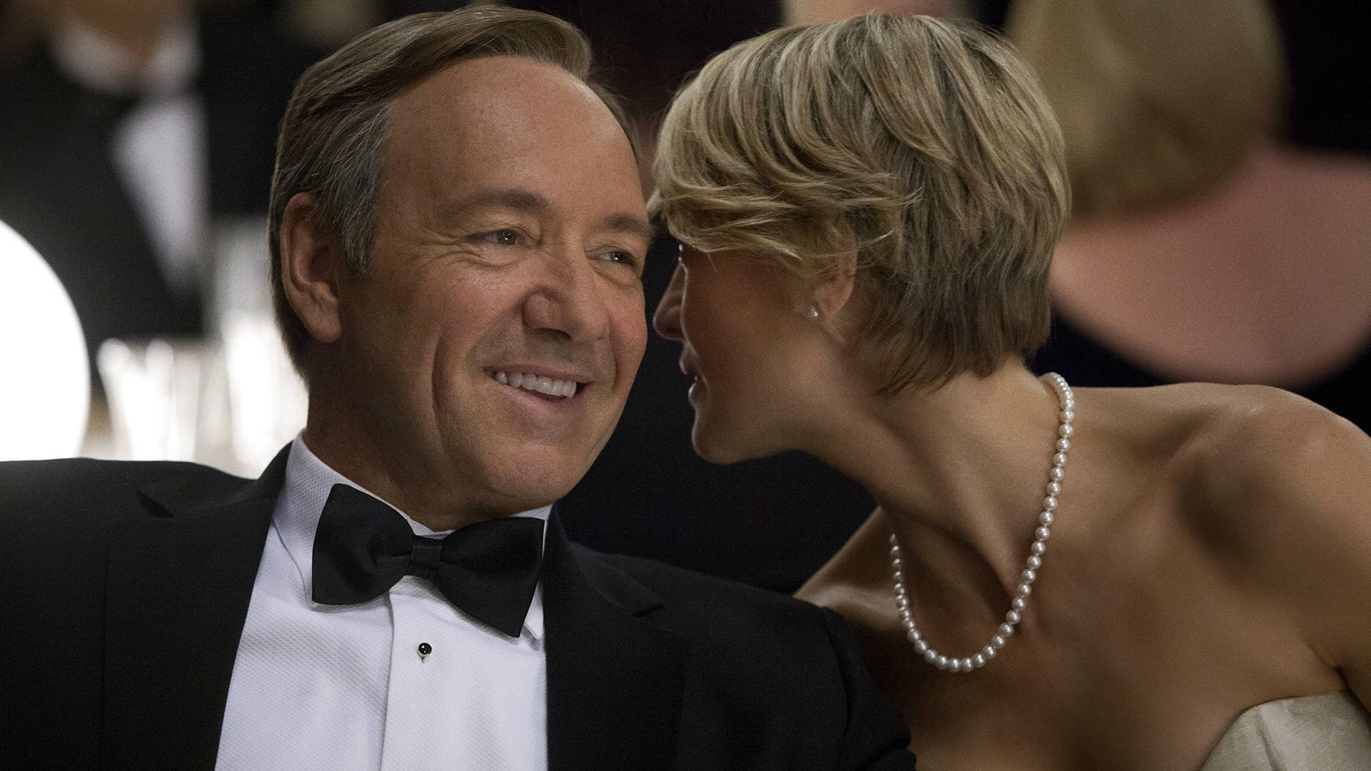 kevin spacey 桌布 壁紙 — 一名身穿燕尾服的男人溫暖地微笑，而一位戴著珍珠項鍊的女人在正式晚宴活動中靠近他。