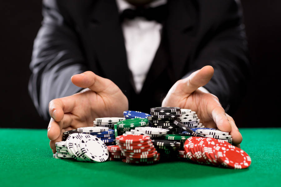 Poker 桌布 壁紙 — 一名身穿燕尾服的男士在綠色毛氈桌上展示一堆色彩繽紛的籌碼。