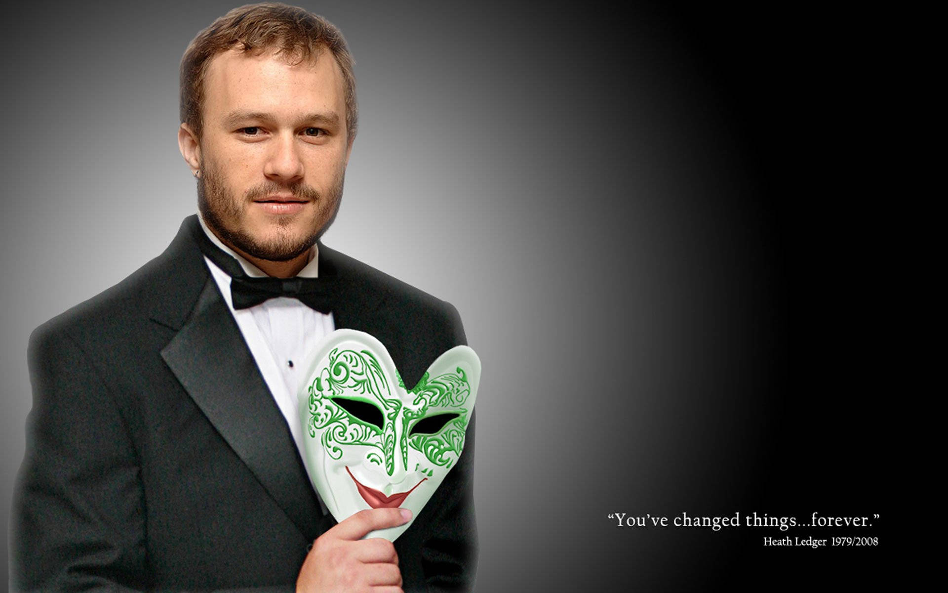 Heath Ledger 桌布 壁紙 — 一名身穿燕尾服的男士手持一個綠色裝飾心形面具，背景為漸變灰色。