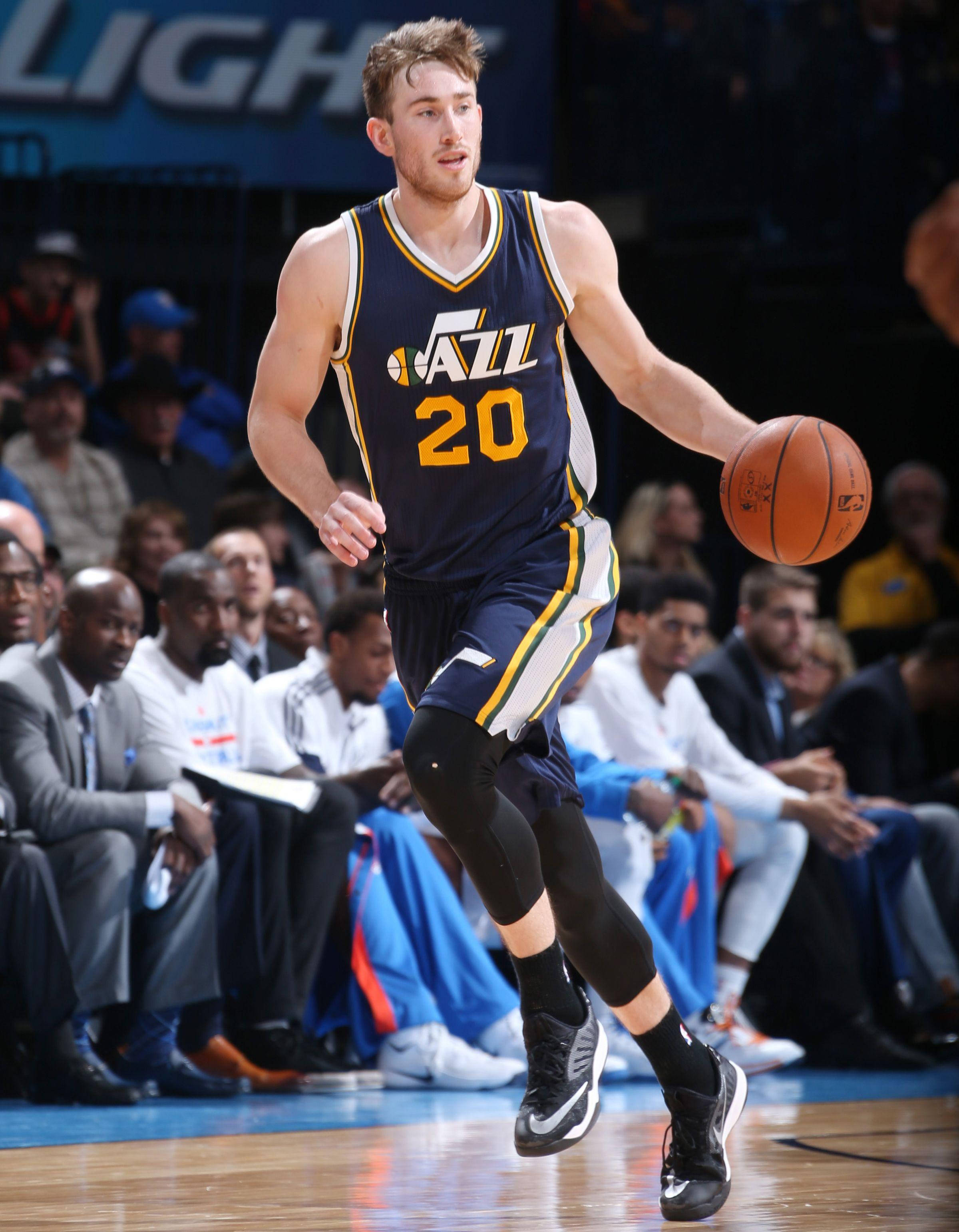 gordon hayward 桌布 壁紙 — 一名身穿爵士隊球衣的籃球運動員在明亮的場館燈光下，於激烈比賽中運球前進。