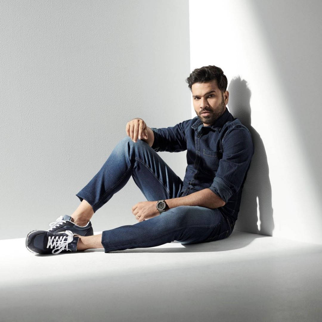 Rohit Sharma 桌布 壁紙 — 一名身穿牛仔布的男子休閒地靠著白色牆壁坐著，強烈的定向光線投射出清晰的陰影。