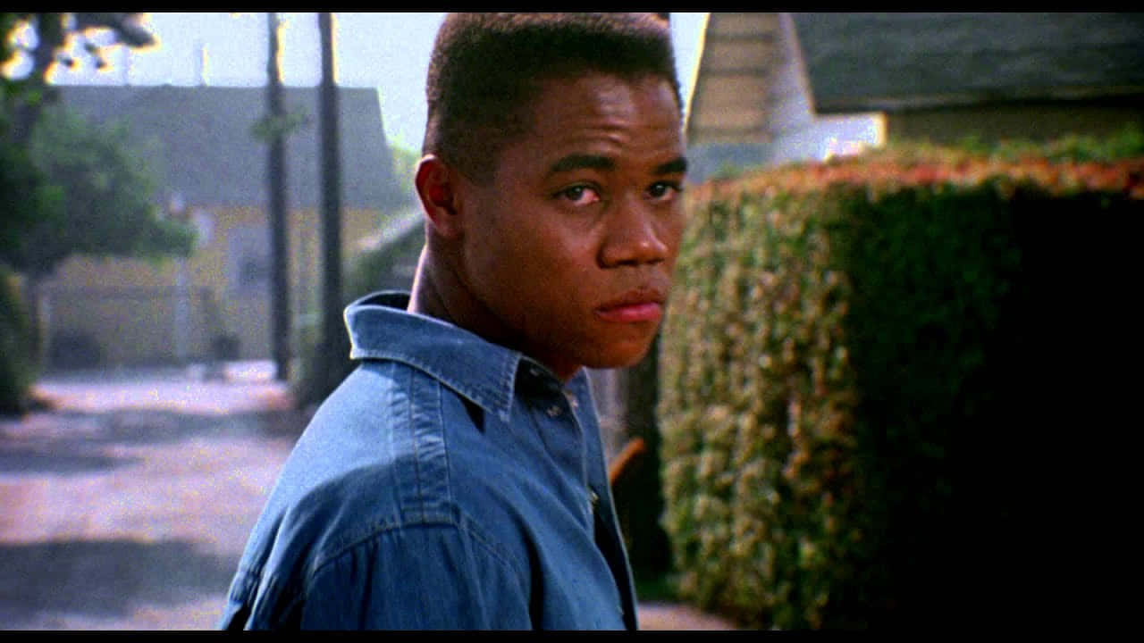 Boyz N The Hood 桌布 壁紙 — 一名身穿牛仔襯衫的年輕男子在郊區街道上，嚴肅地轉頭越過肩膀。