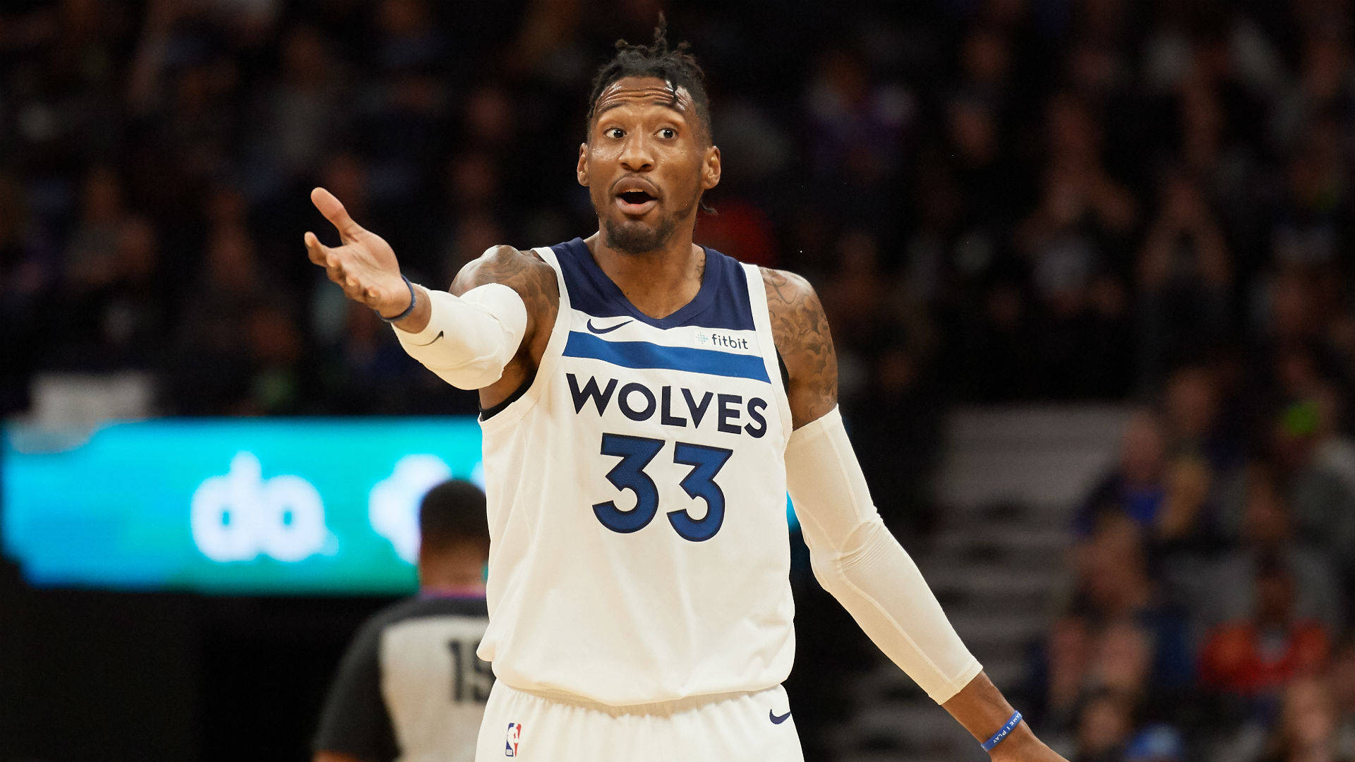 robert covington 桌布 壁紙 — 一名身穿狼隊球衣的籃球運動員在場館燈光下比賽時用力做手勢。