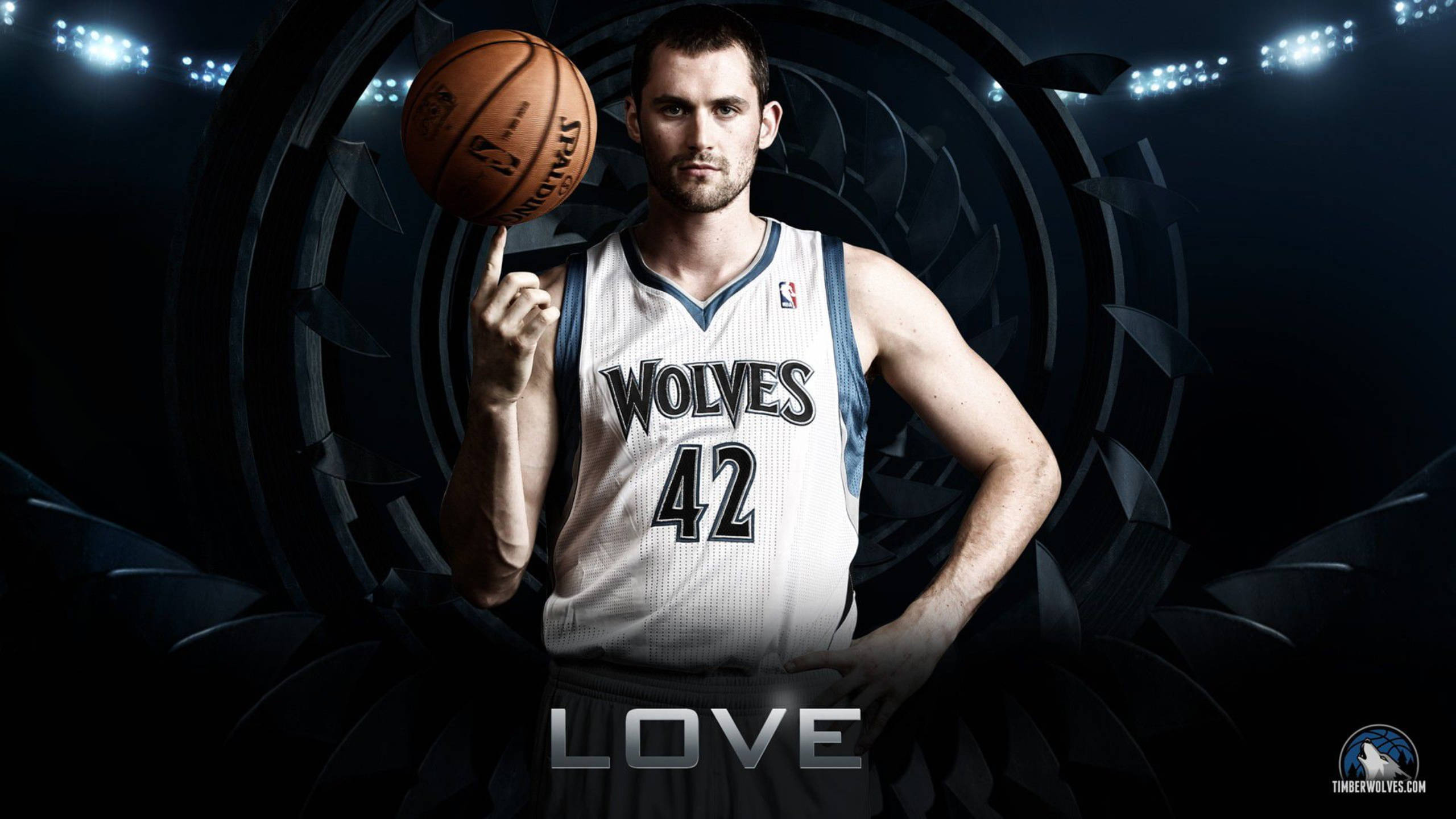 Timberwolves 桌布 壁紙 — 一名身穿狼隊球衣的籃球運動員在黑暗的體育場背景下，伴隨著發光的燈光，將球平衡在手指上。