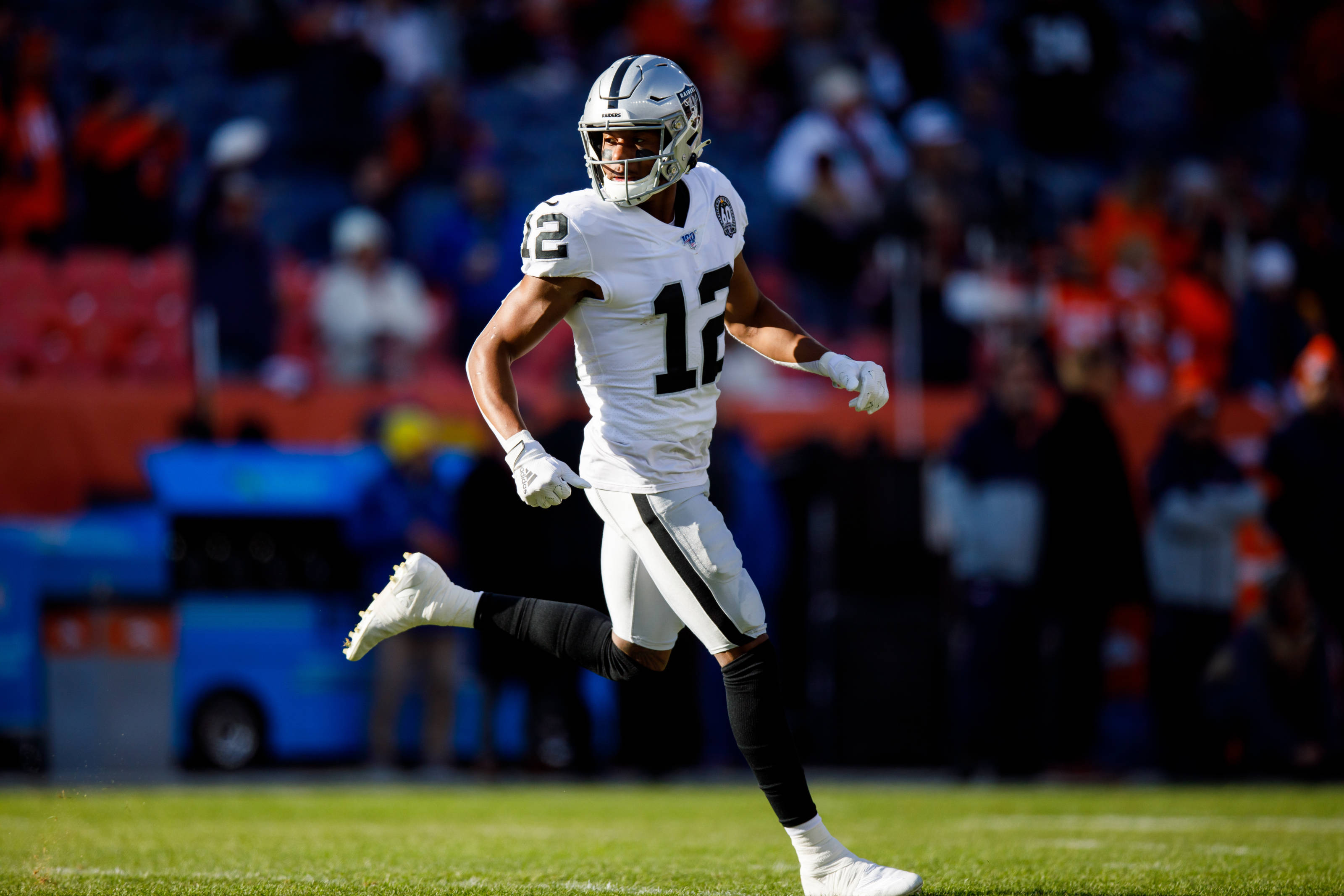 zay jones 桌布 壁紙 — 一名身穿白色12號球衣的足球運動員在陽光明媚的綠色球場上衝刺，背景是模糊的體育場觀眾。
