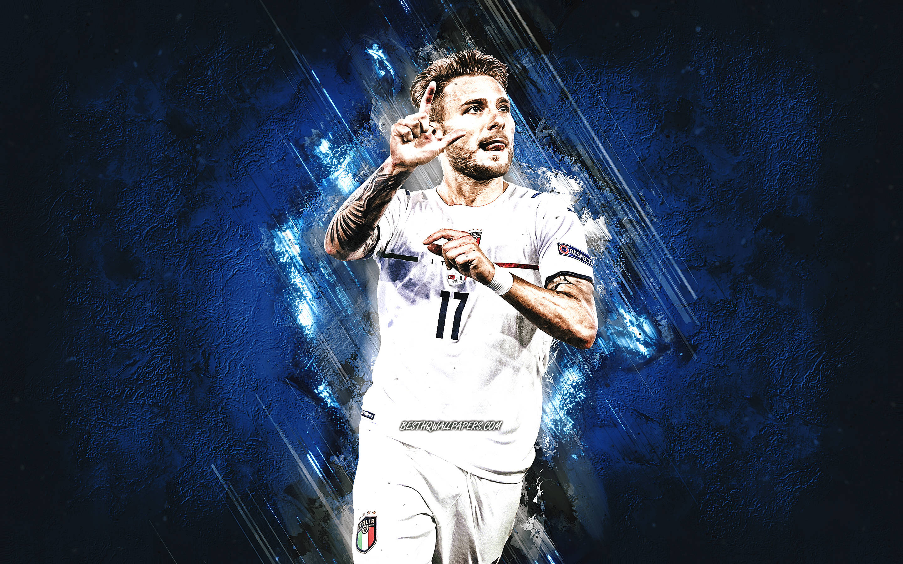 ciro immobile 桌布 壁紙 — 一名身穿白色17號球衣的足球運動員在動感藍色抽象背景前舉手慶祝。