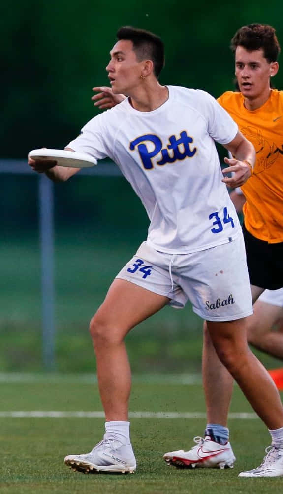 Android Ultimate Frisbee 桌布 壁紙 — 一名身穿白色34號球衣的匹特飛盤選手準備投擲，而一名身穿橙色球衣的競爭對手在草地上密切注視。