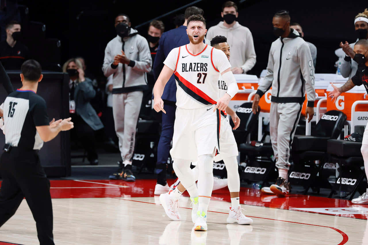 籃球 桌布 壁紙 — 一名身穿白色Blazers球衣、背號27的籃球運動員在拋光球場上慶祝，隊友和工作人員在他周圍反應。