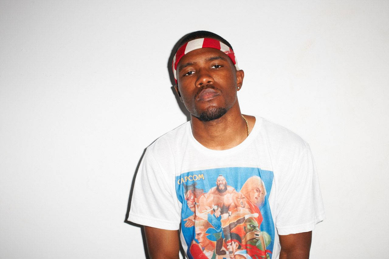 Frank Ocean 桌布 壁紙 — 一名身穿白色Capcom電玩T恤和紅白頭帶的男子在純白牆前擺姿勢。