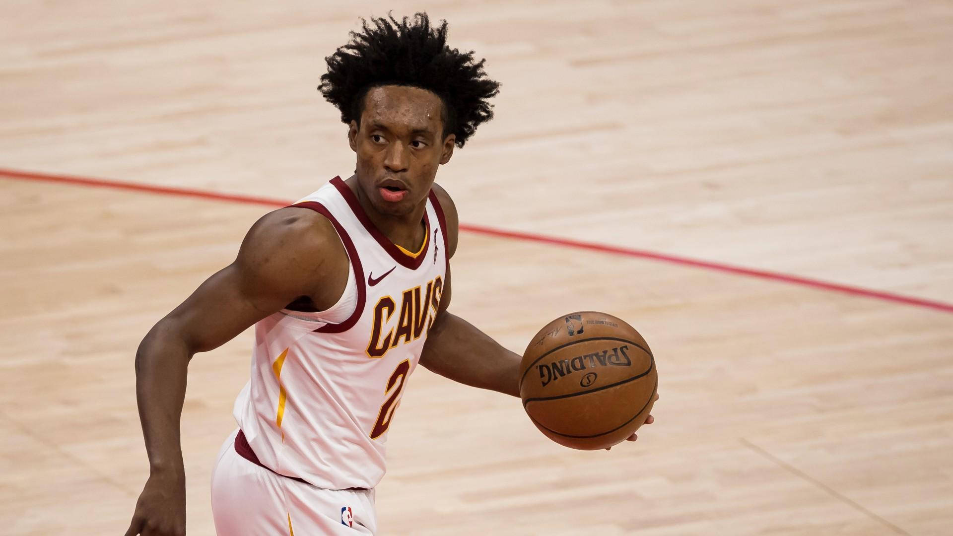Cleveland Cavaliers 桌布 壁紙 — 一名身穿白色Cavs球衣的籃球運動員在木地板上專注地運著Spalding籃球。
