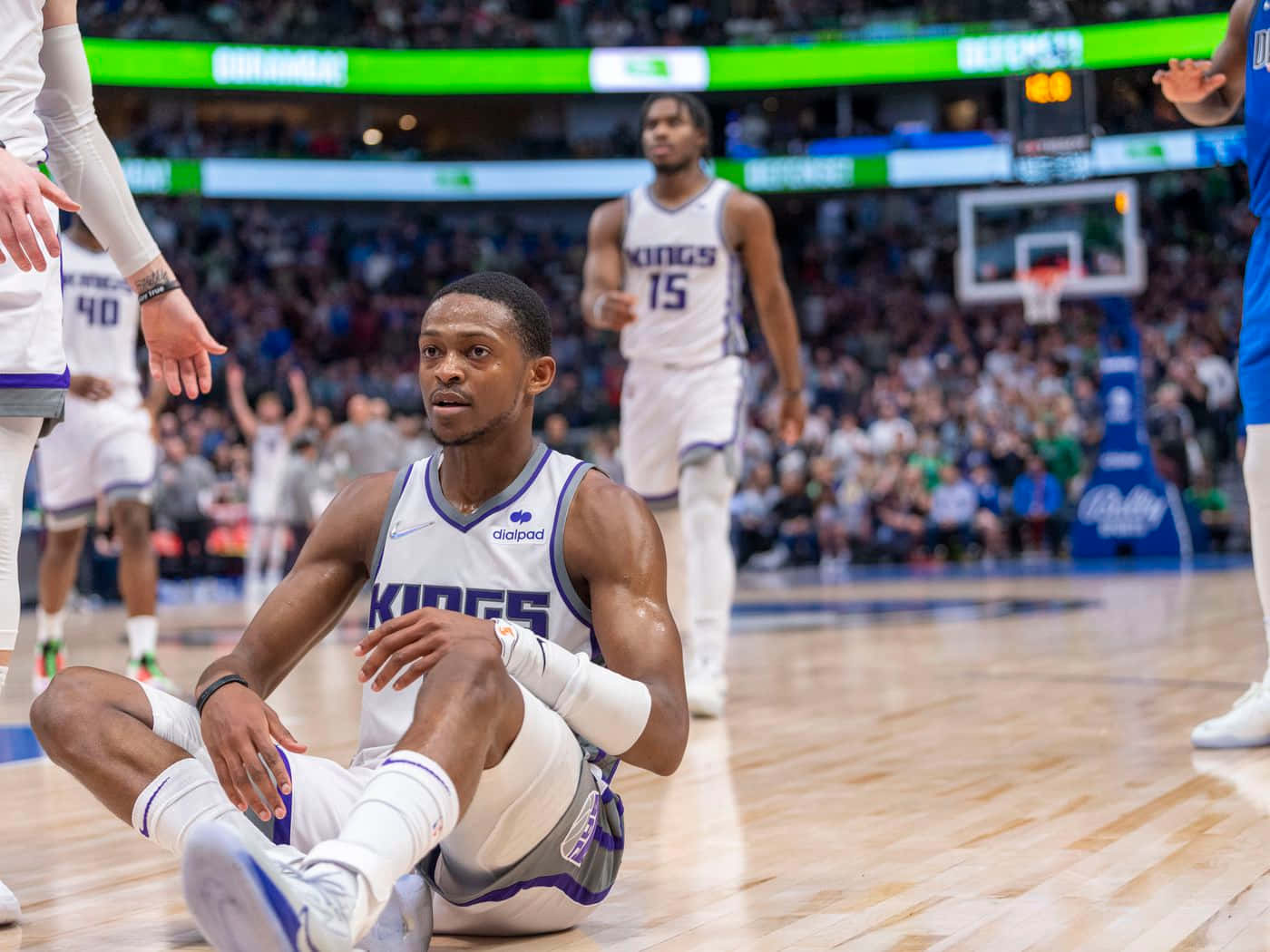 NBA 桌布 壁紙 — 一名身穿白色Kings球衣的籃球運動員在比賽期間坐在硬木地板上，專注地向上看。