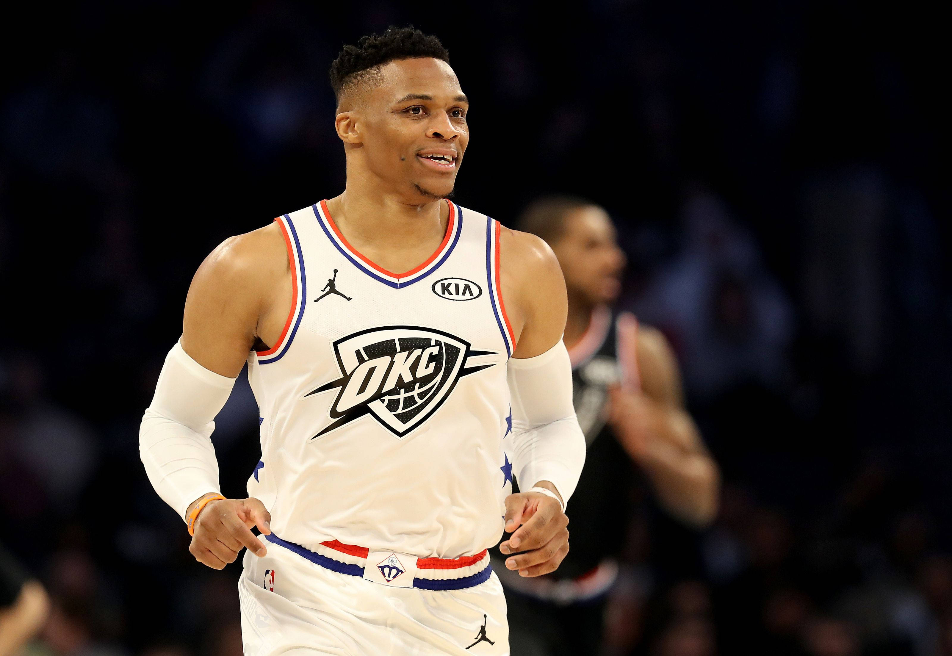 Westbrook 桌布 壁紙 — 一名身穿白色OKC球衣的籃球運動員在明亮的場館燈光下，在比賽中專注地奔跑。