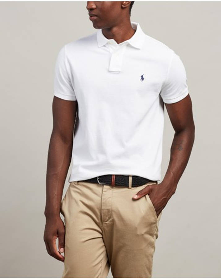 ralph lauren 桌布 壁紙 — 一名身穿白色Polo衫、帶有細小藍色標誌的男子，在中性背景前自信地站立。