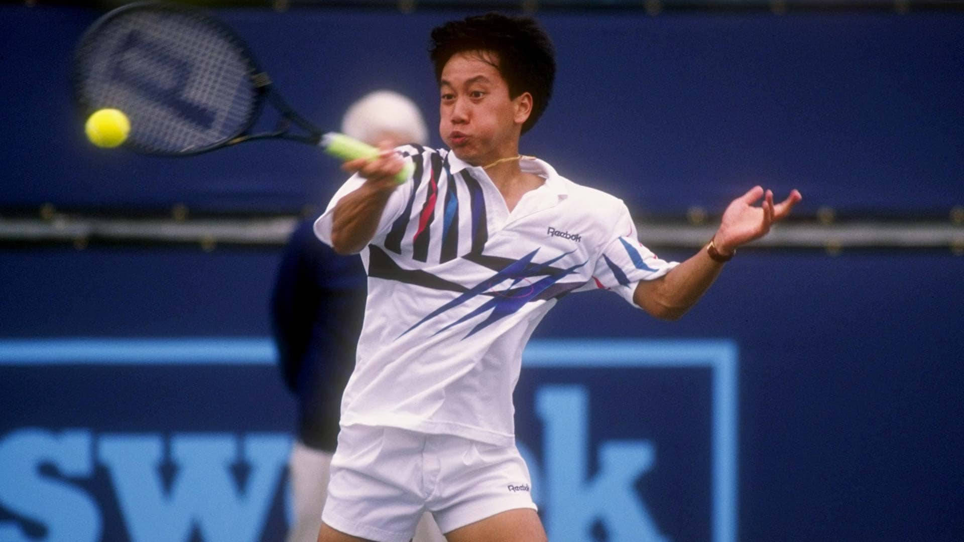網球 桌布 壁紙 — 一名身穿白色Reebok裝備的男網球選手在藍色球場上揮拍擊打黃色網球。