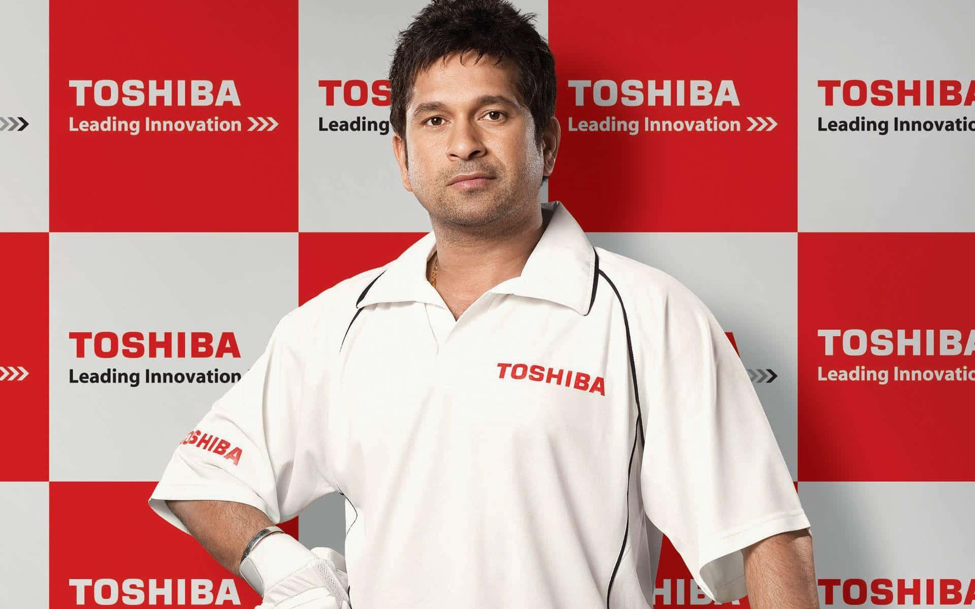 Sachin Tendulkar 桌布 壁紙 — 一名身穿白色Toshiba Polo衫的男子自信地站在紅灰格紋的Toshiba品牌背景前。