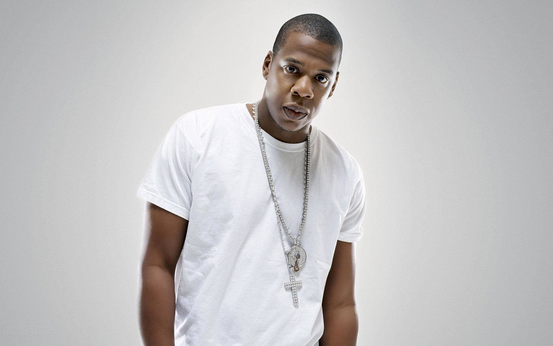 Jay-z 桌布 壁紙 — 一名身穿白色T恤和銀色鏈條項鍊的男子，在純灰色背景前擺出驚訝的表情。