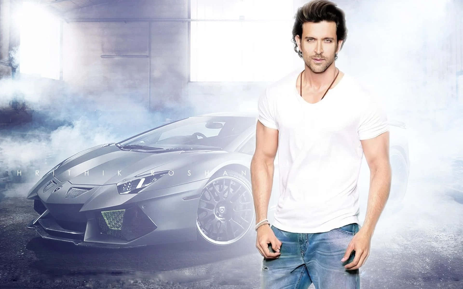 Bollywood Hero 桌布 壁紙 — 一名身穿白色T恤的男子自信地站在一輛時尚的消光黑色藍寶堅尼旁邊，背景是煙霧瀰漫的工業車庫。
