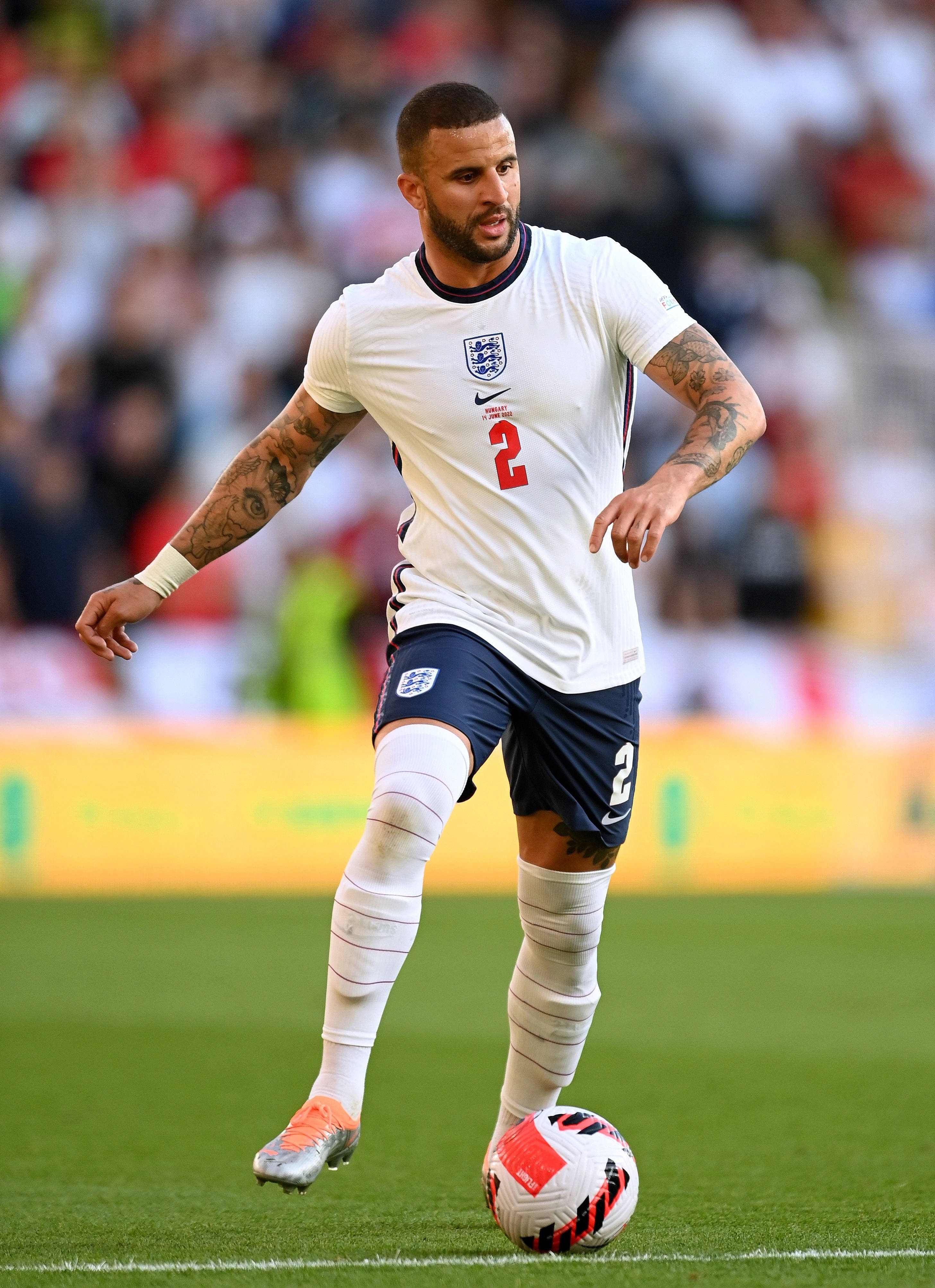 Kyle Walker 桌布 壁紙 — 一名身穿白色二號球衣的英格蘭足球員，在明亮的日光下，於充滿活力的綠色球場上盤帶一個紅白相間的足球。