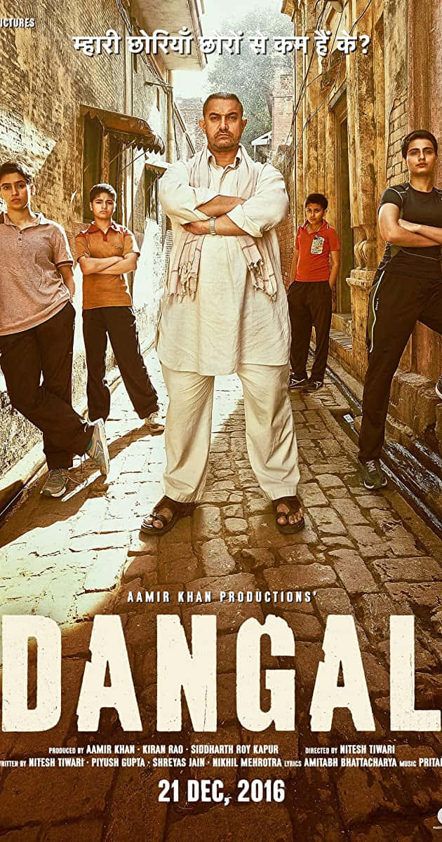 Aamir Khan 桌布 壁紙 — 一名身穿白色傳統服飾的男子自信地交叉雙臂，站在一條陽光普照的狹窄小巷中，兩旁有年輕男孩。