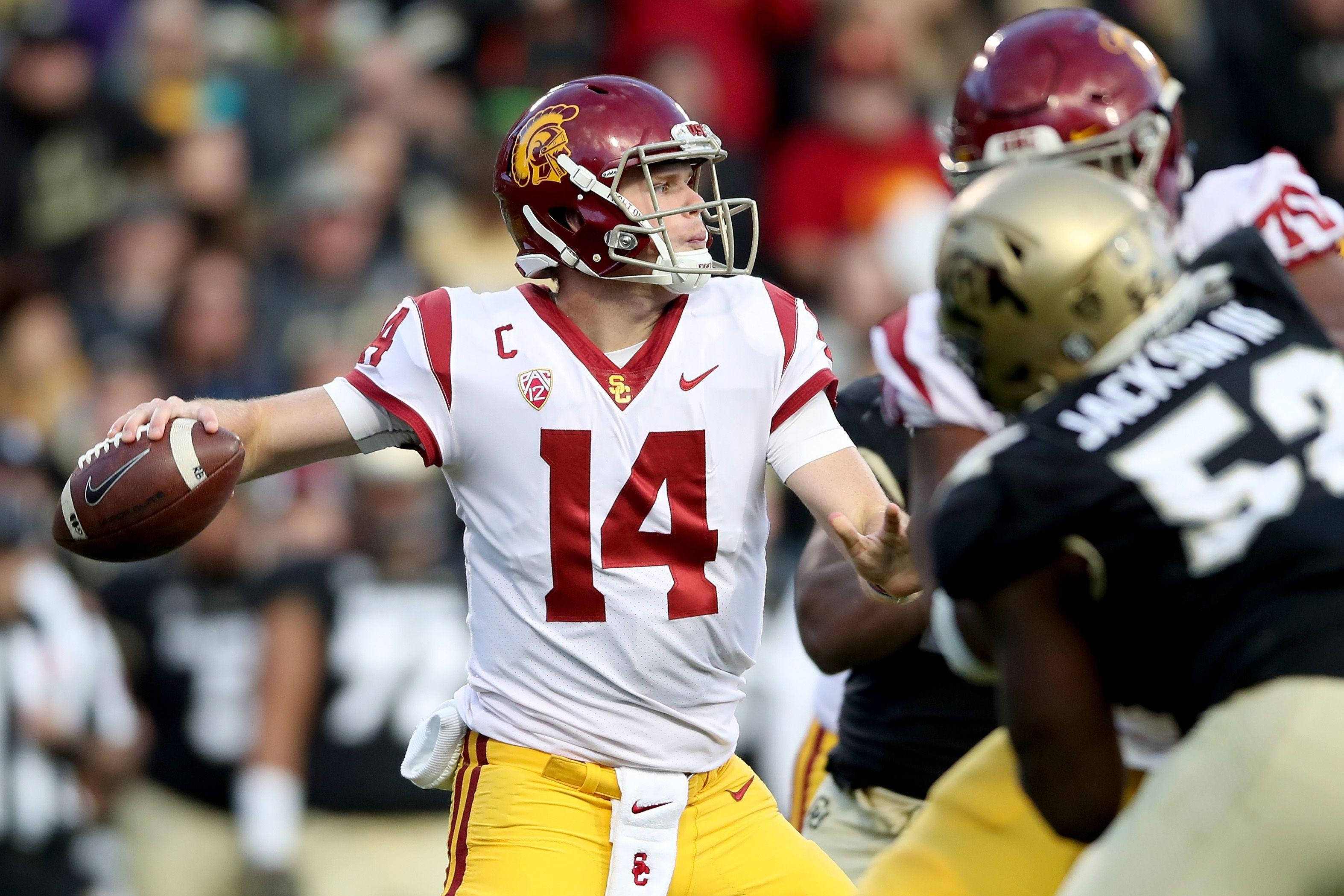 Football Players 桌布 壁紙 — 一名身穿白色和紅色制服的大學美式足球四分衛在比賽中，在防守球員逼近時擲出球。