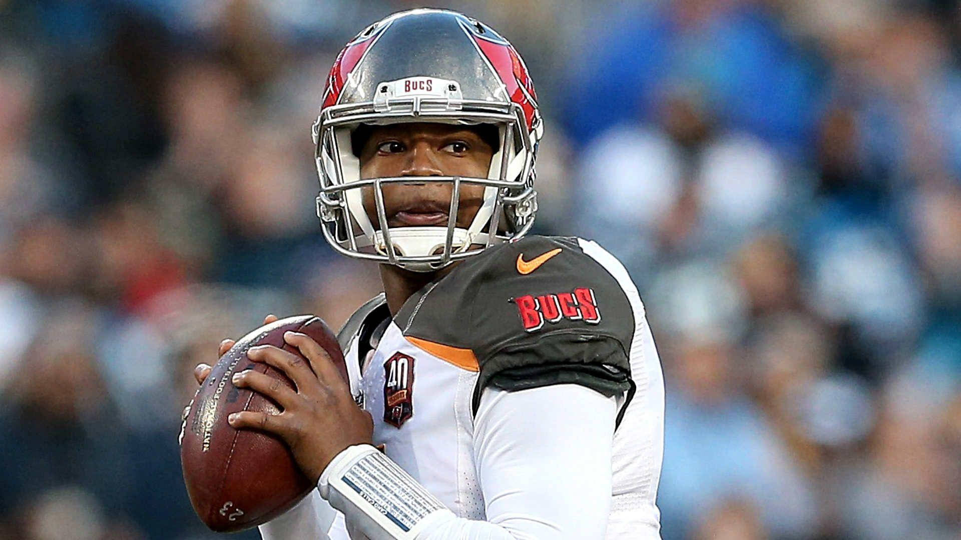 運動 桌布 壁紙 — 一名身穿白色和紅色球衣的坦帕灣海盜隊四分衛在比賽中手持橄欖球準備傳球，背景是模糊的體育場人群。
