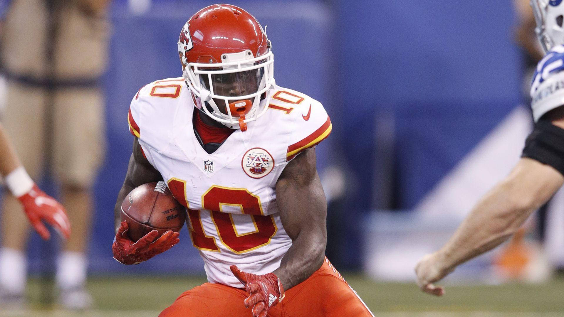 Tyreek Hill 桌布 壁紙 — 一名身穿白色和紅色球衣的堪薩斯城酋長隊美式足球員在體育場燈光下比賽中持球奔跑。
