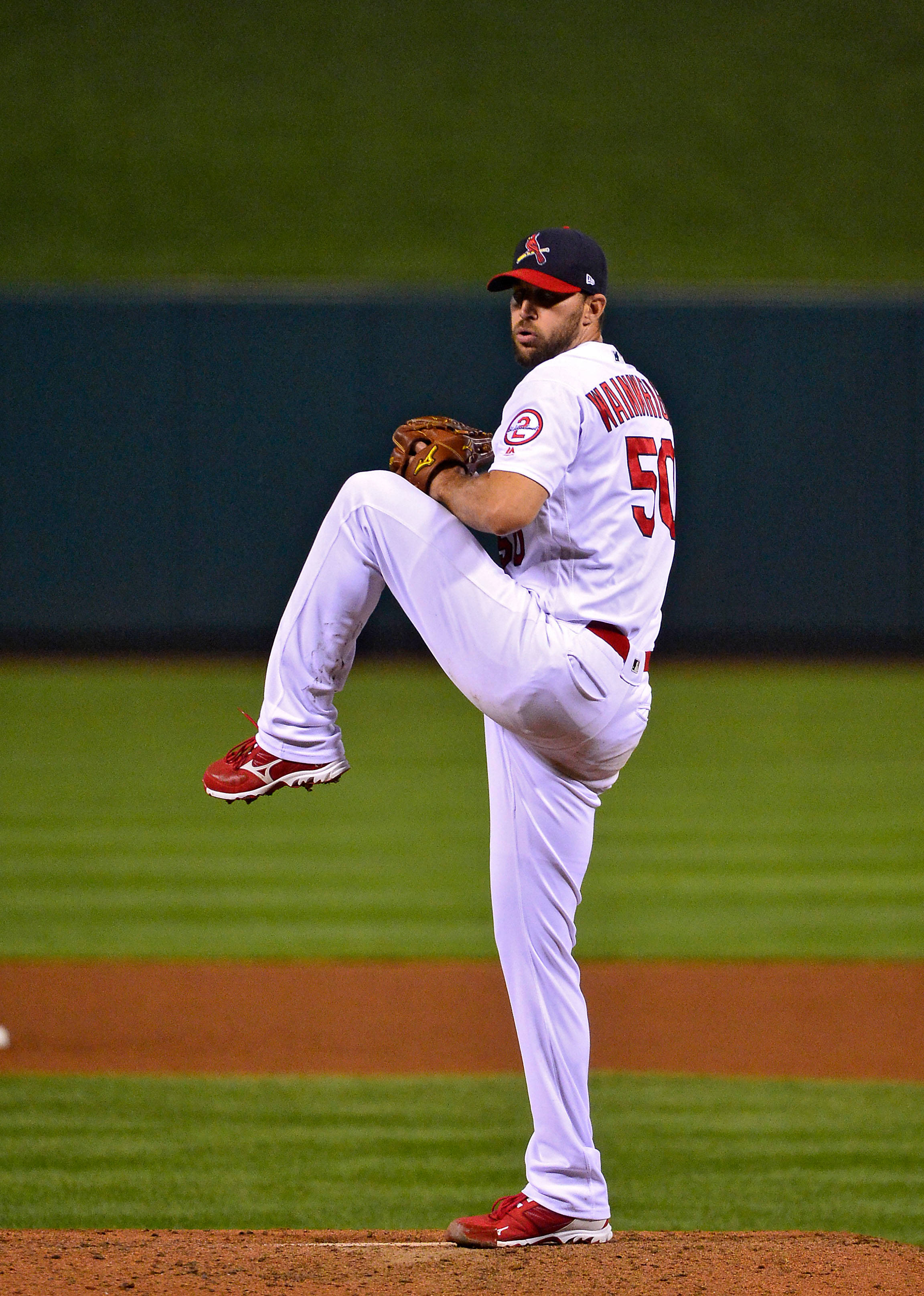 Adam Wainwright 桌布 壁紙 — 一名身穿白色和紅色球衣的棒球投手在夜間光線充足的球場上投球。