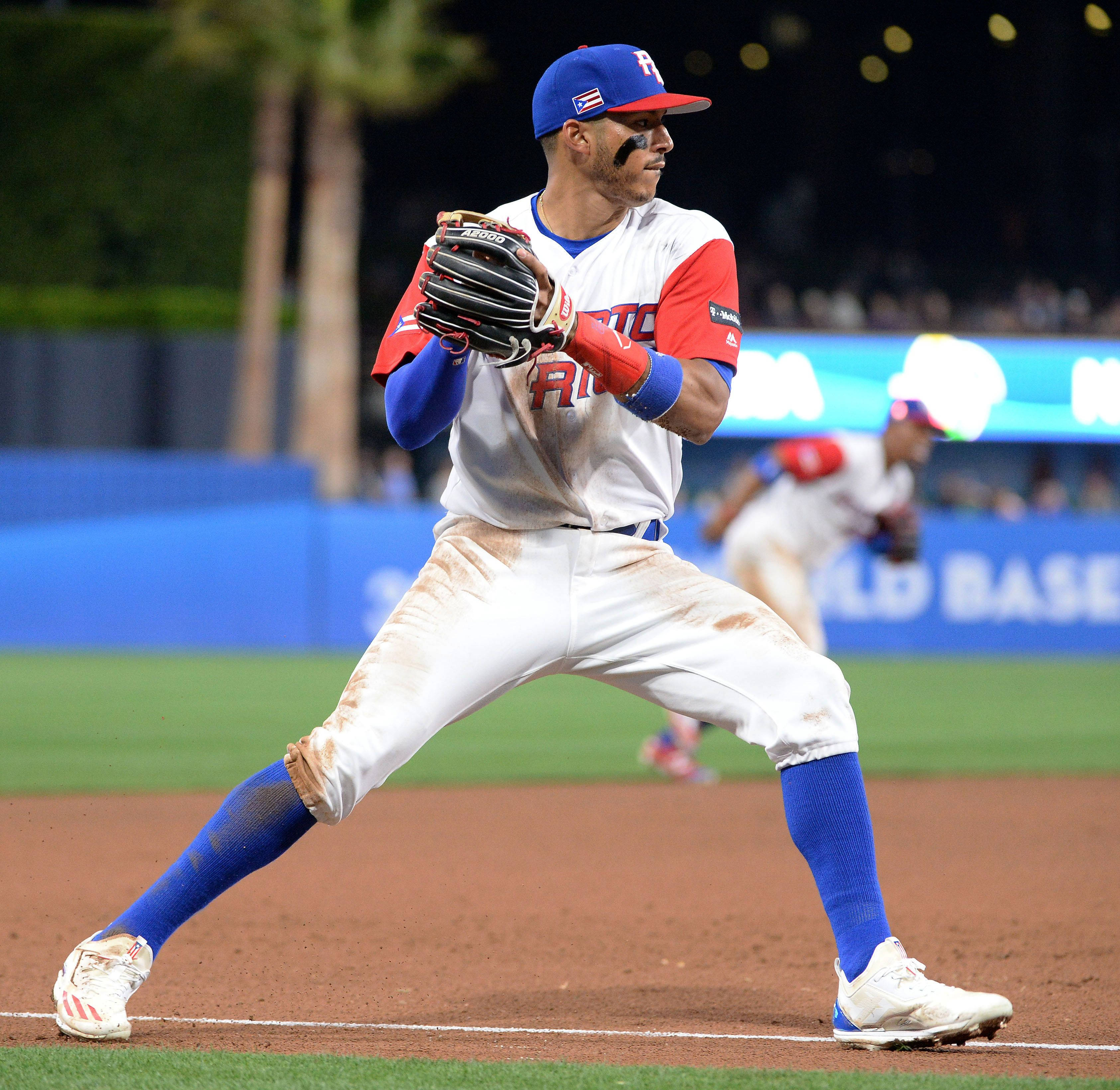 Carlos Correa 桌布 壁紙 — 一名身穿白色和紅色球衣的棒球選手在夜間球場燈光下低蹲在泥地內野上。