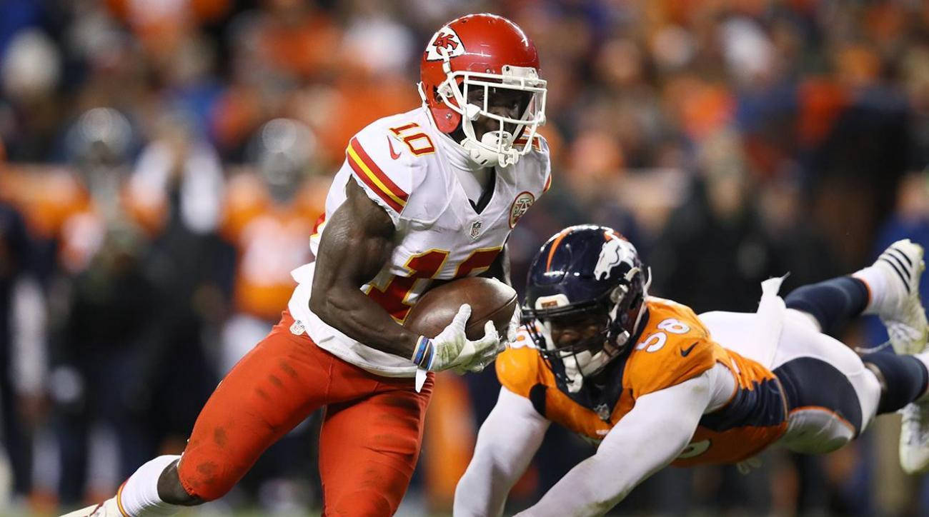 Tyreek Hill 桌布 壁紙 — 一名身穿白色和紅色的堪薩斯城酋長隊球員在夜間比賽中帶著橄欖球奔跑，而丹佛野馬隊的防守球員飛身鏟截他。