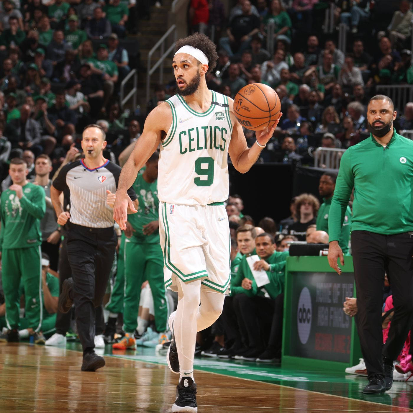 NBA 桌布 壁紙 — 一名身穿白色和綠色球衣的波士頓塞爾提克籃球運動員在激烈的比賽中運球，背景是熱情高漲的球迷。