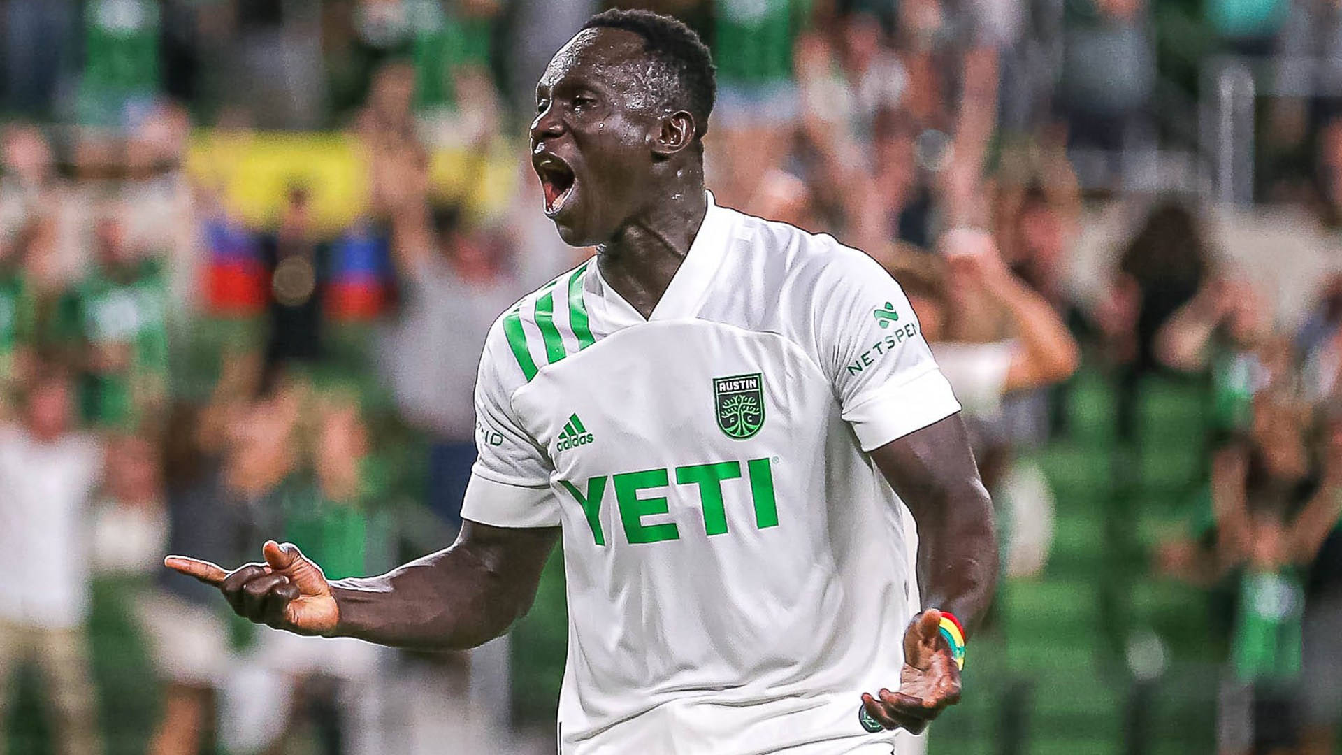 Austin Fc 桌布 壁紙 — 一名身穿白色和綠色球衣的足球運動員在球場上張開雙臂勝利地吶喊。