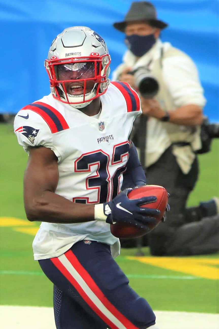 Devin Mccourty 桌布 壁紙 — 一名身穿白色和藍色球衣的新英格蘭愛國者隊美式足球員在日間比賽中帶球奔跑。