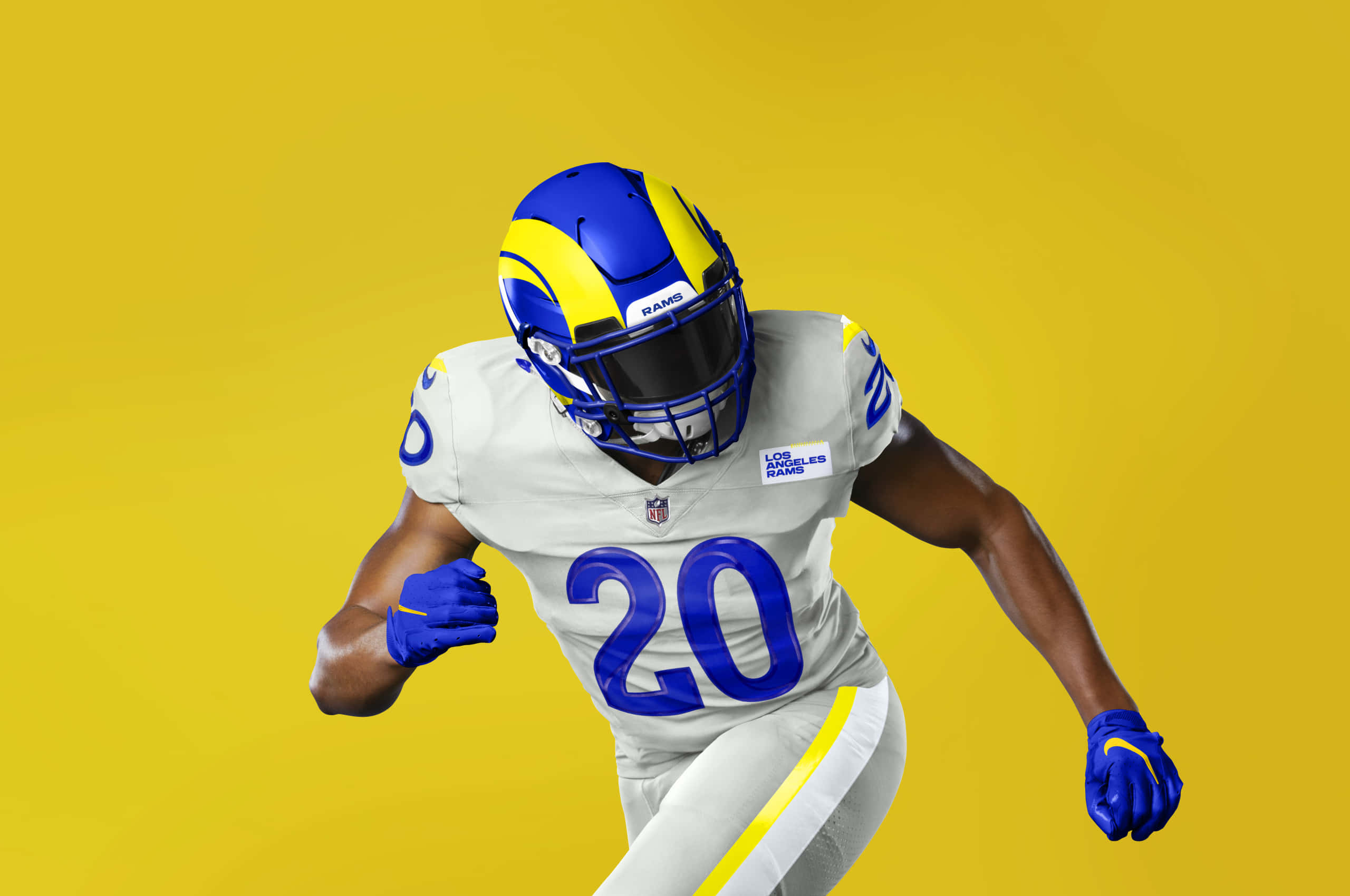 Football Players 桌布 壁紙 — 一名身穿白色和藍色球衣的洛杉磯公羊隊美式足球員在純黃色背景上動態衝刺。