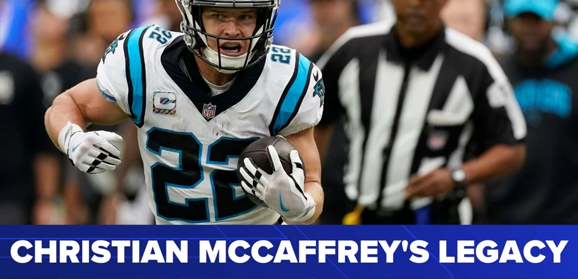 Christian Mccaffrey 桌布 壁紙 — 一名身穿白色和藍色球衣的足球員在比賽中帶球奔跑，背景有裁判。